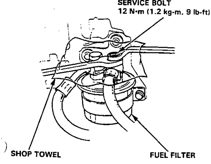 Close-up of the fuel filter with the service bolt on top, used to relieve fuel pressure. A shop towel is wrapped around the area to catch fuel.