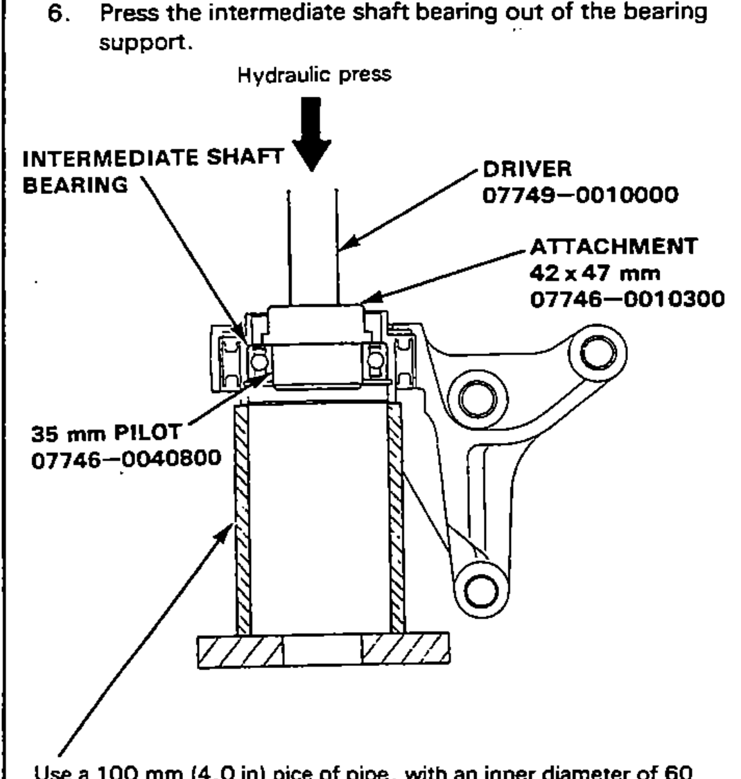 Pressing the intermediate shaft bearing out of the bearing support on a hydraulic press using a driver, 42x47 mm attachment, and 35 mm pilot, with the support set on a length of pipe.