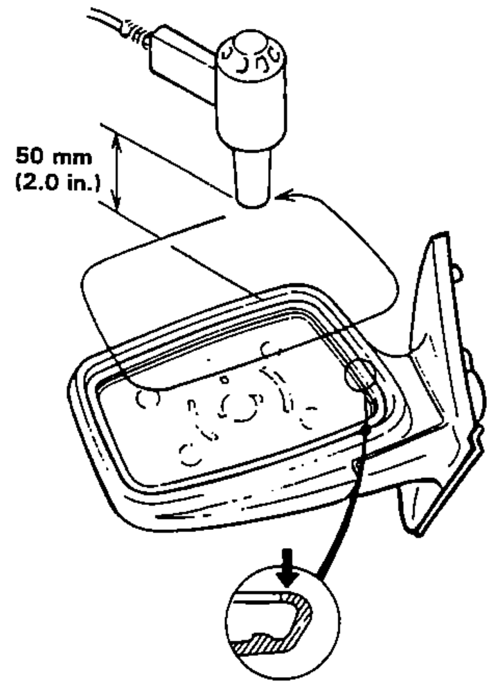 Mirror glass replacement, step 1. Shows a low-powered heat gun held about 50 mm (2.0 in.) from the edge of the mirror glass to remove it from the mirror case, with a detail of the glass edge.