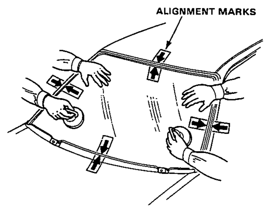 Two people using suction cups to set the windshield glass into the opening, aligning it with the alignment marks and pushing down on the glass to seat it on the adhesive.