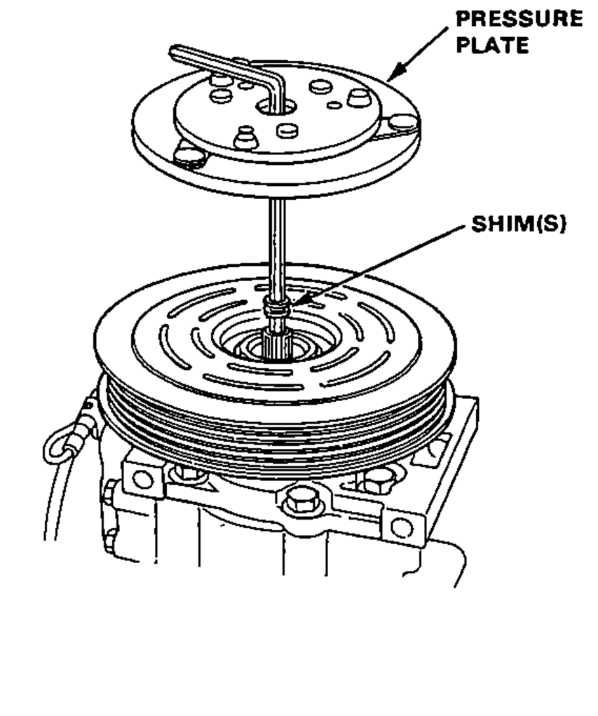 Removal of the pressure plate and shim(s) from the compressor clutch pulley; pressure plate lifted off with shim(s) between it and the pulley.