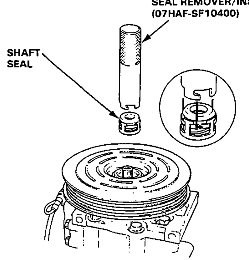 Removing the shaft seal from the compressor using the seal remover/installer tool; an inset shows the tool cutout engaging the metal pawl of the seal case.
