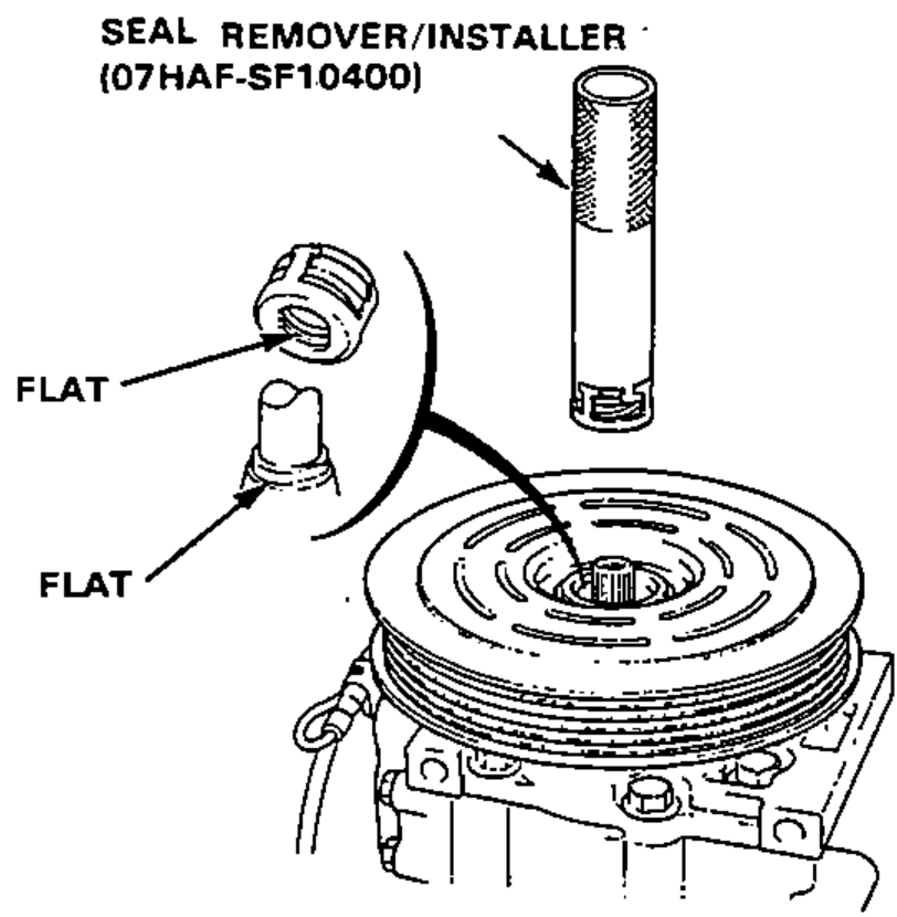 Installing the shaft seal onto the compressor shaft with the seal remover/installer tool, aligning the seal case flats with the shaft flats; leader lines label the two FLAT surfaces.
