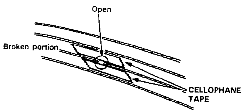 Close-up of a broken defogger wire showing the open break, the broken portion, and cellophane tape masked above and below the break.